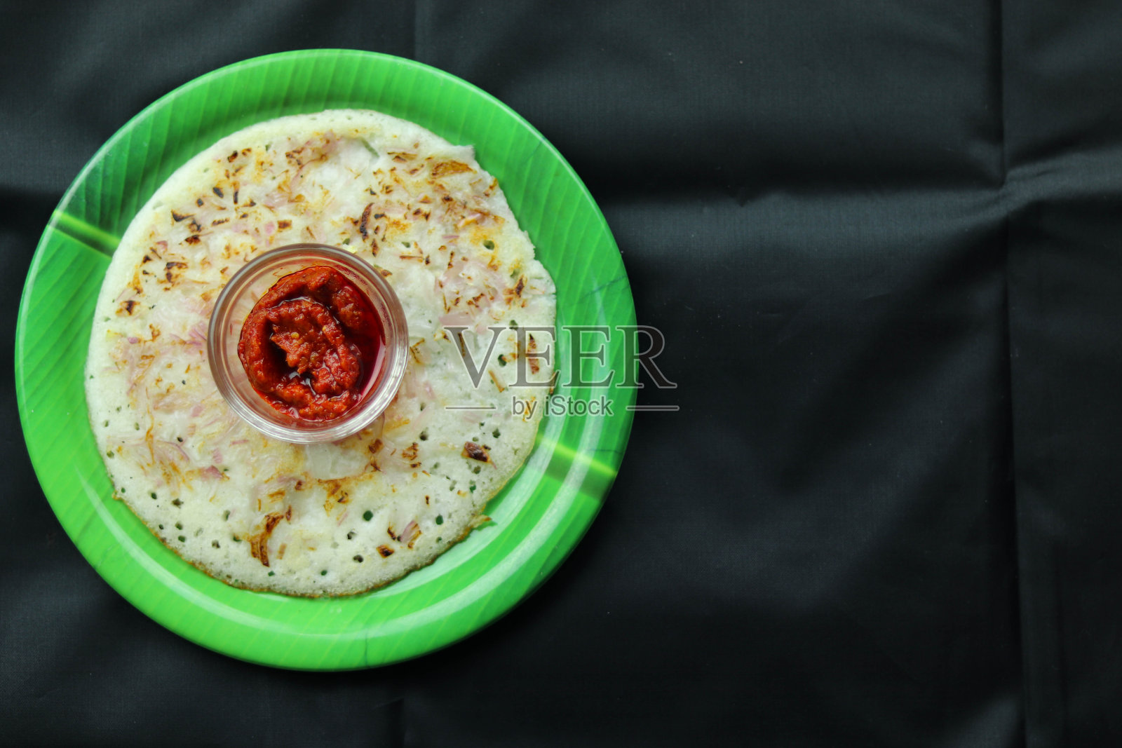 选择Focus on South Indian Breakfast pickle and Onion Uttapam in Black Background and Blank Space照片摄影图片