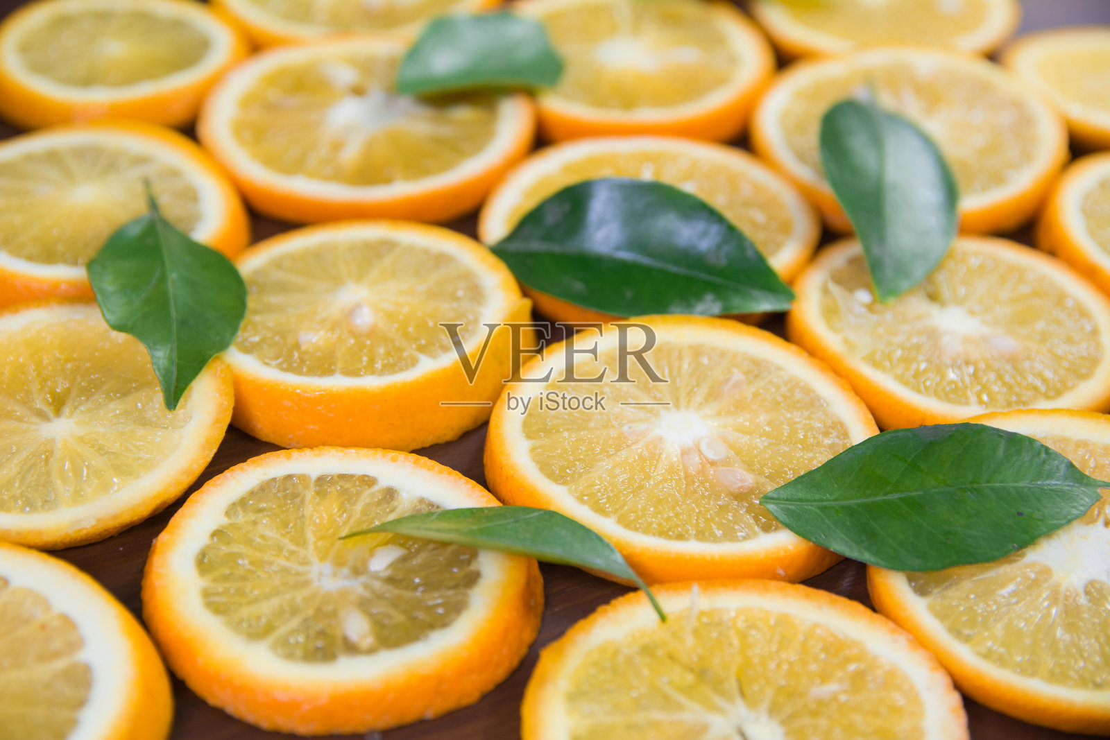 橘片和橘叶的特写，以随机的模式放置在一张木桌上，最适合橙色的生意和设计新鲜、多汁和多汁照片摄影图片