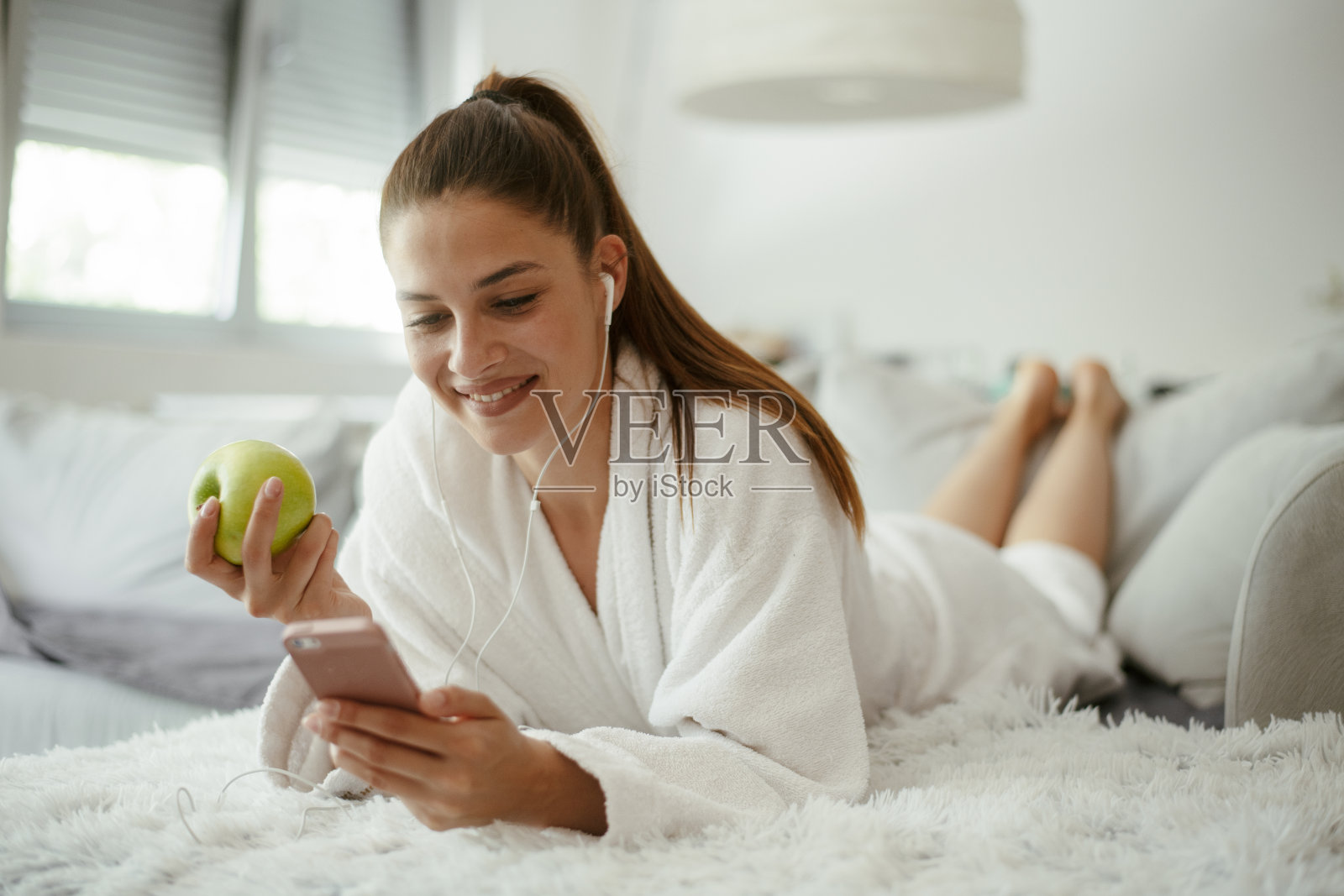 年轻漂亮的女人发短信上网在家里的沙发上。库存图片照片摄影图片