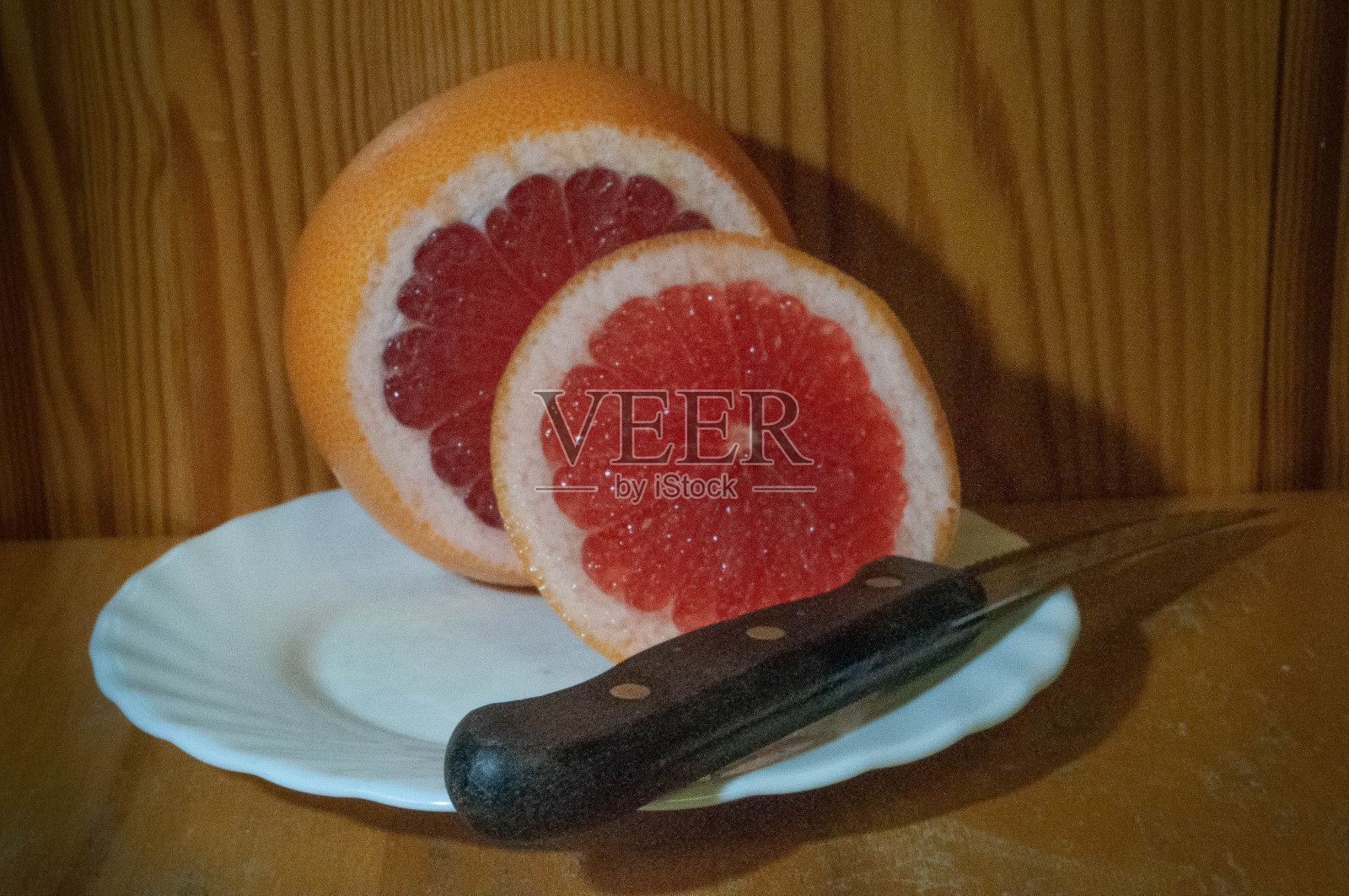 白色盘子上切开的熟透的粉红色葡萄柚照片摄影图片