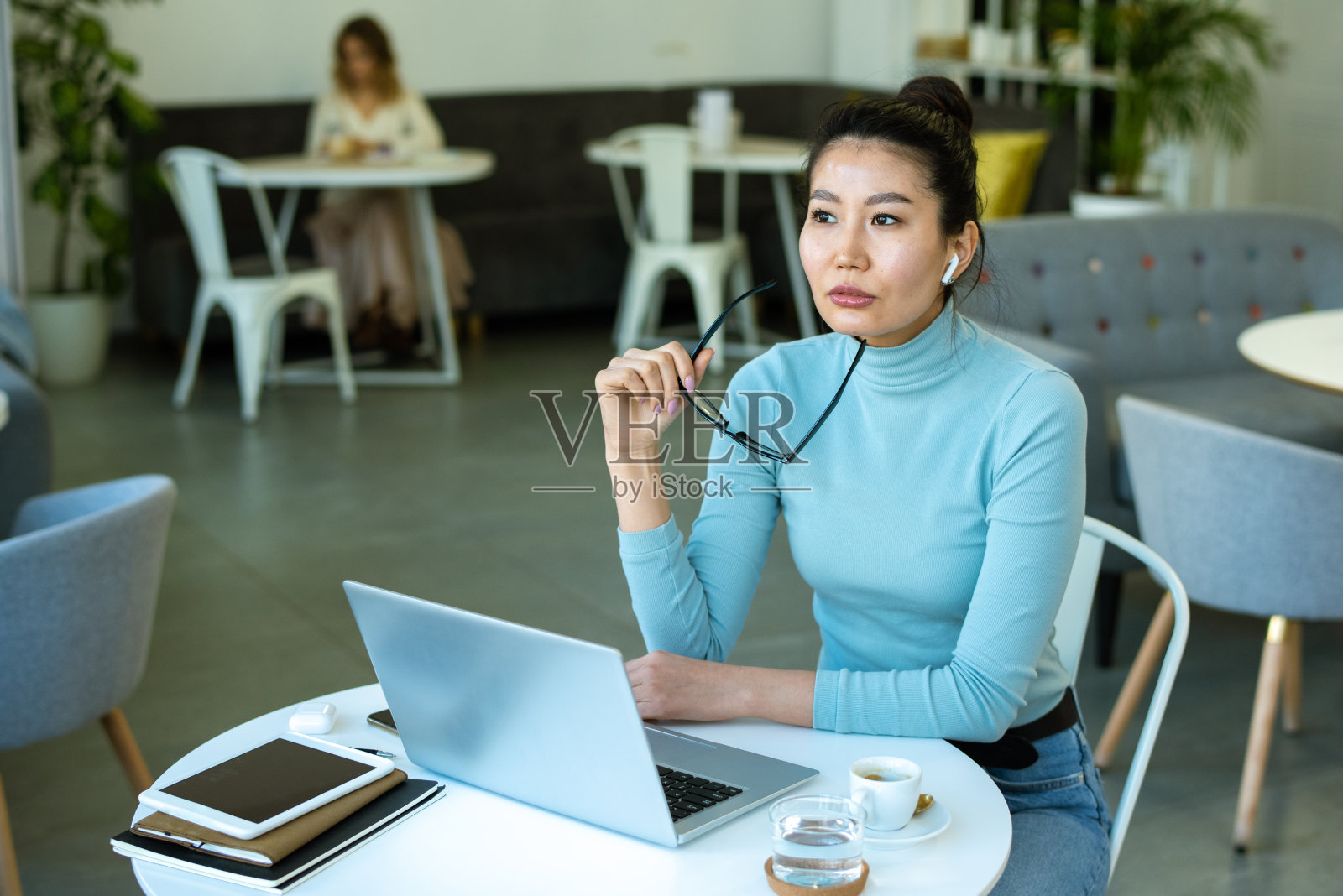 一个穿着休闲装沉思的年轻女子在咖啡馆的笔记本电脑前分析数据照片摄影图片