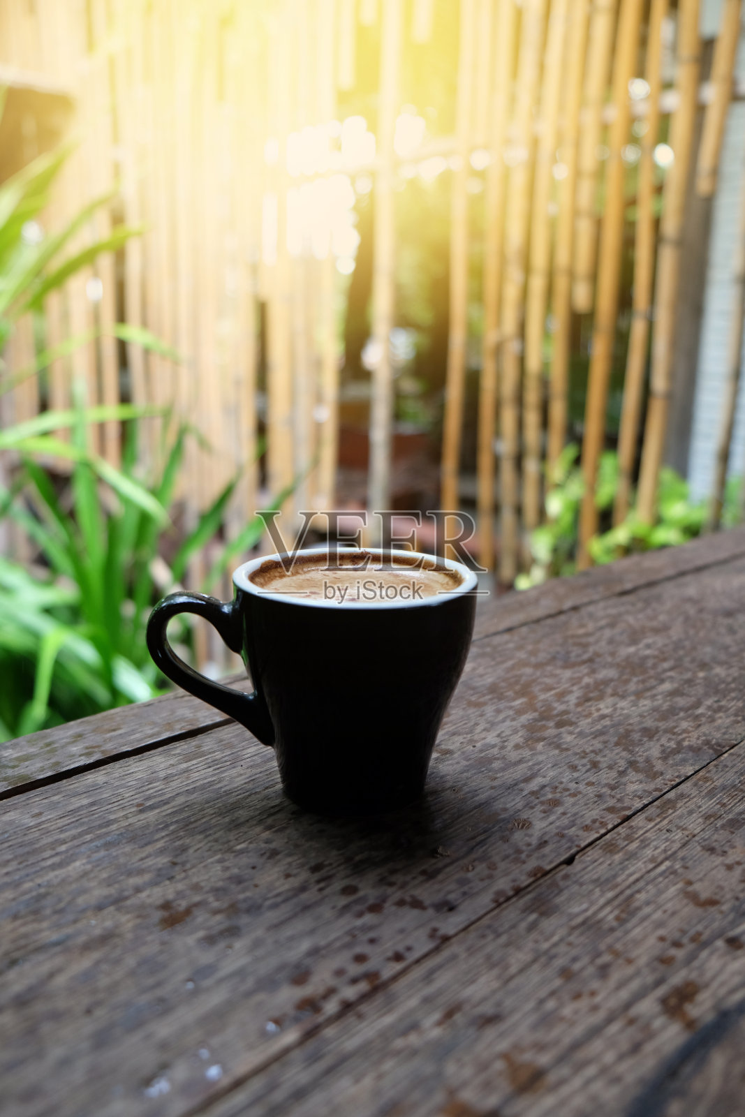 热咖啡杯放在木桌上，以花园为自然背景，清晨雨天的种植园背景——意象照片摄影图片