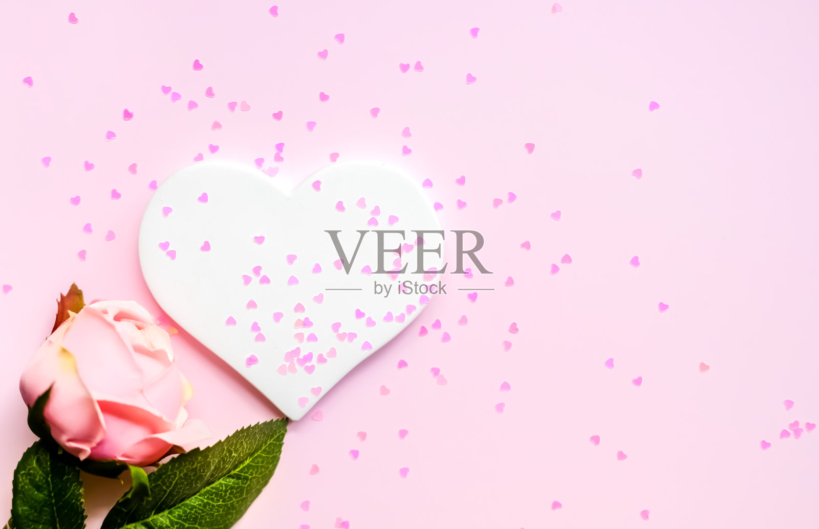 粉红色背景上的人工粉色玫瑰和白色的心。放置文字，平放概念。照片摄影图片