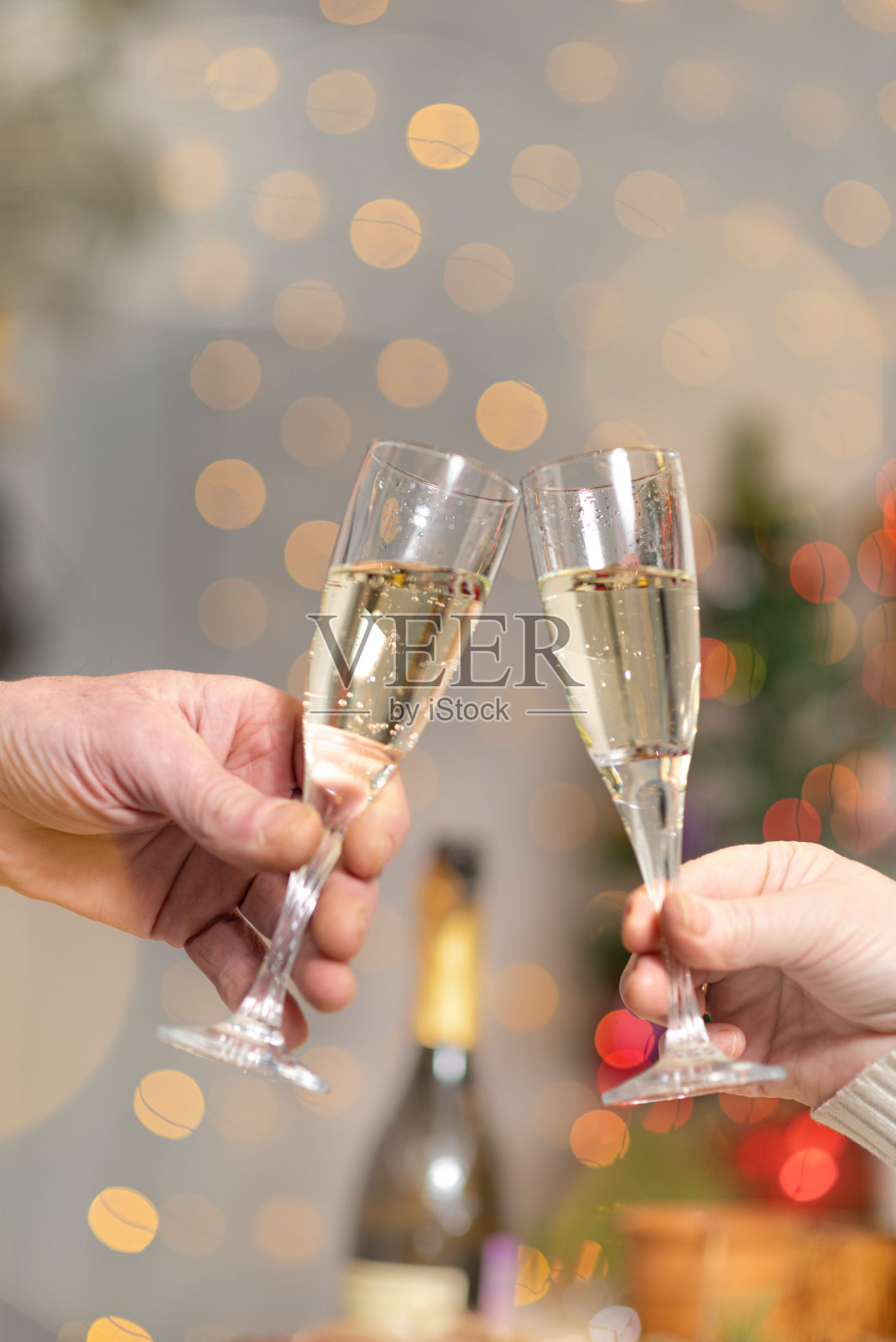 在新年灯光的模糊背景上，手里拿着几杯香槟照片摄影图片