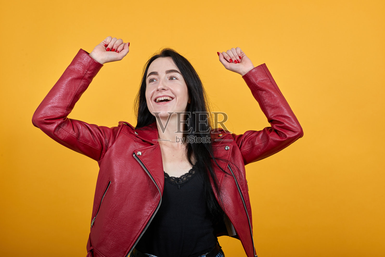 年轻女子抬起头，举起双手，握紧拳头，像胜利者一样照片摄影图片