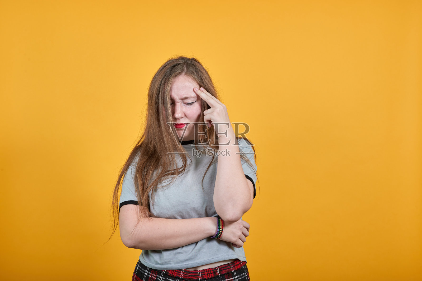 漂亮的年轻女人看起来很滑稽，思考问题，头疼照片摄影图片