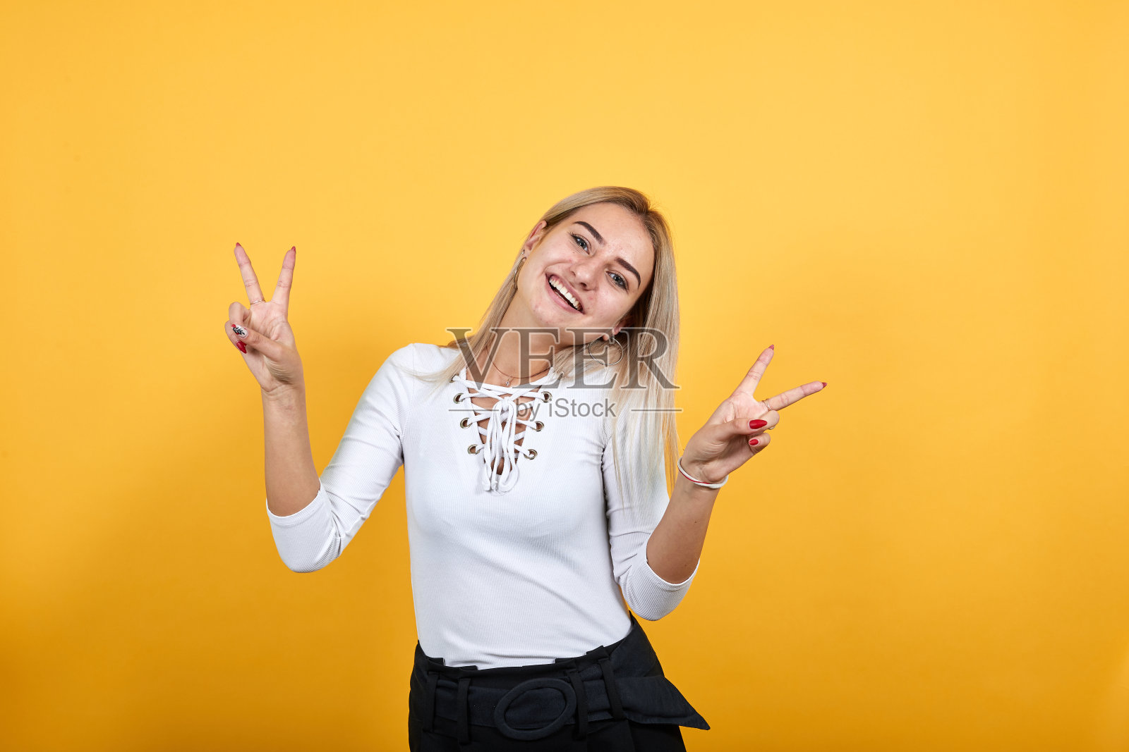 女人用食指指着一边，摆出胜利的姿势，看着镜头照片摄影图片