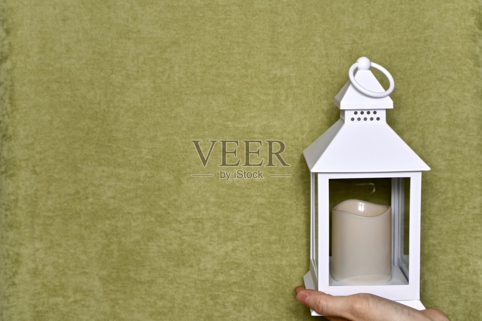 一种装饰灯，在一个女性的手掌上有一个垂饰，水平的框架，在一个绿色的背景。照片摄影图片