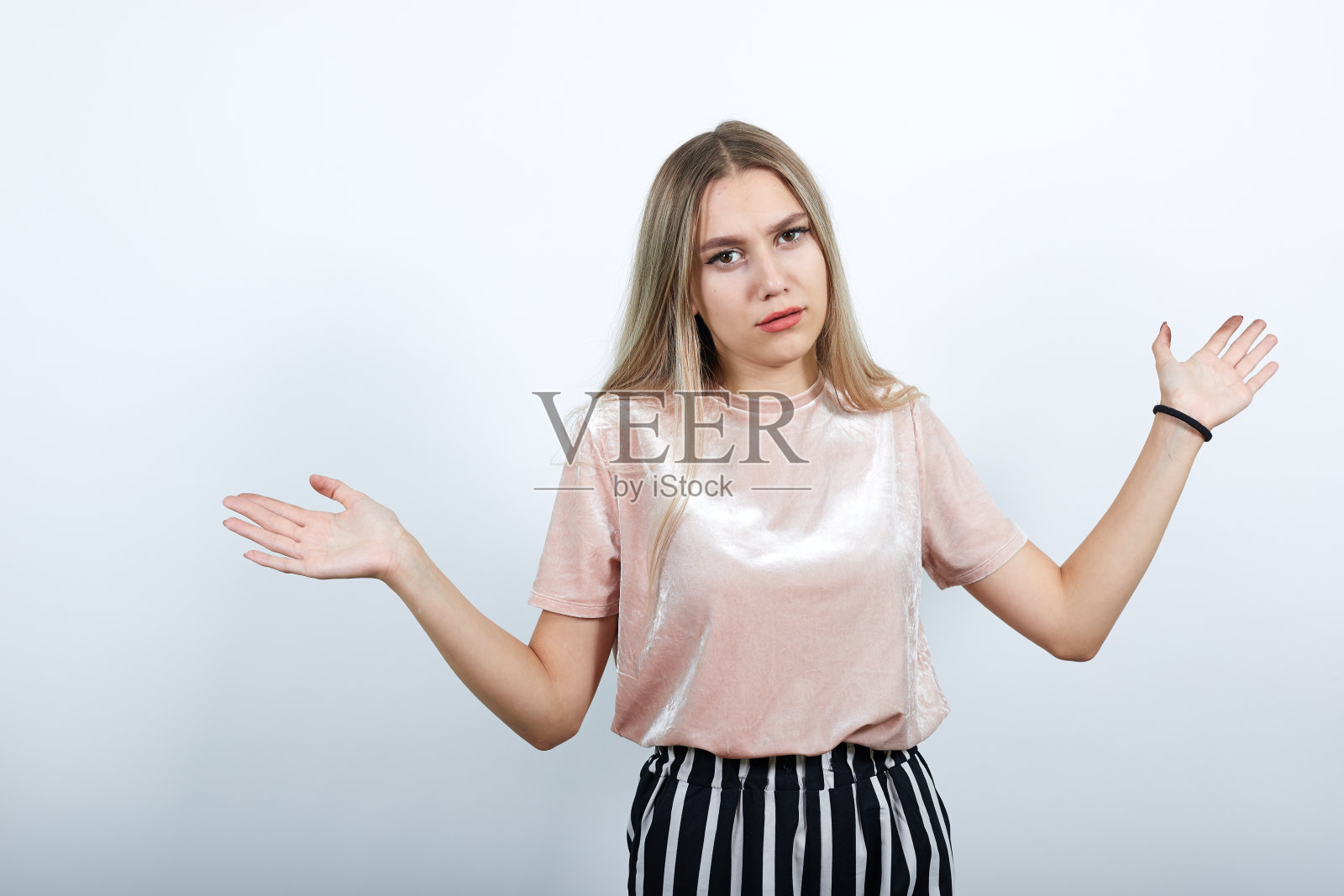 身着淡色衬衫的年轻女子震惊了，她张开双手，看着照相机照片摄影图片