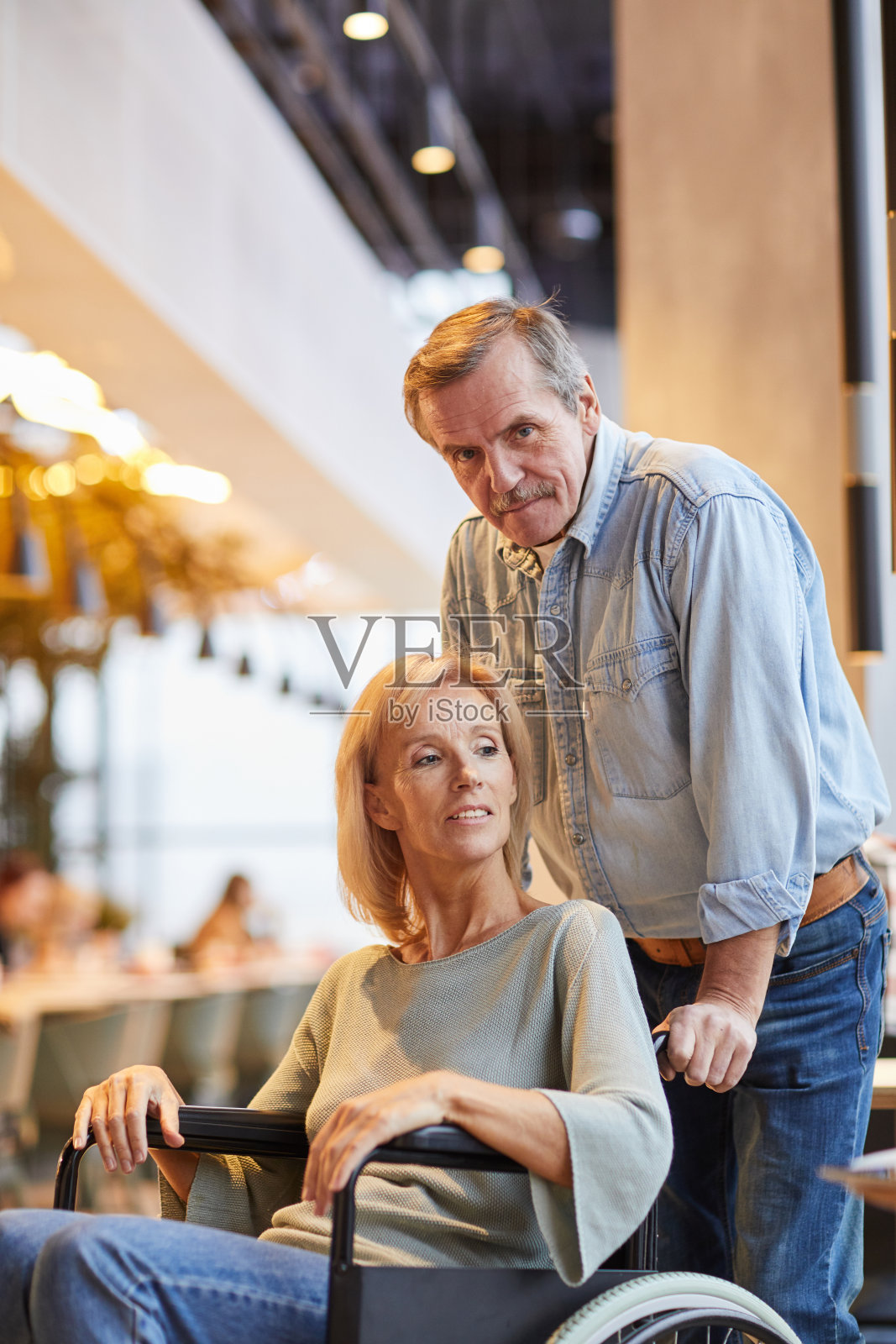 内容细致的高级男子在牛仔装推轮椅与美丽的妻子在咖啡馆肖像照片摄影图片