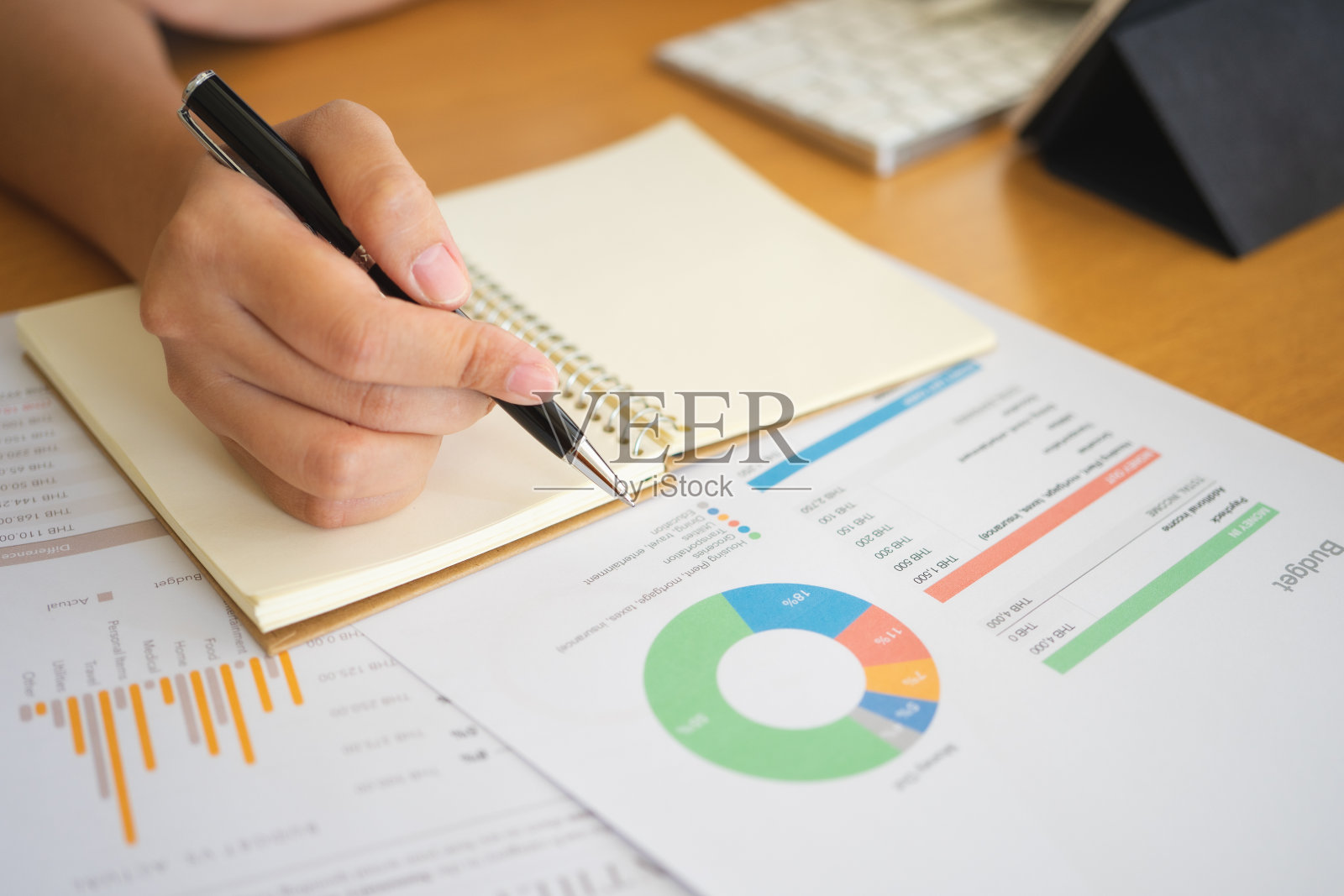 近距离拍摄的女商人的手拿着一支笔写在纸上的东西在办公室的前景。记录的概念。使用智能手机平板电脑。自由职业，商业理念照片摄影图片