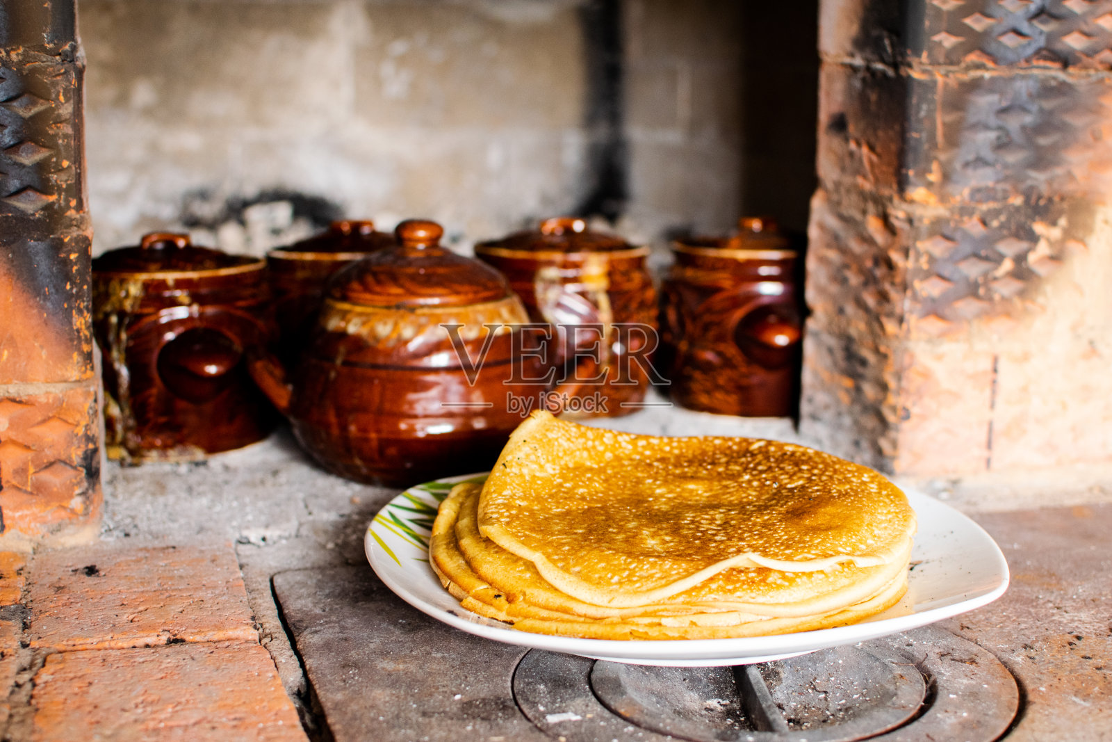 玫瑰色的煎饼在俄罗斯的炉子里煮。Maslenitsa。照片摄影图片