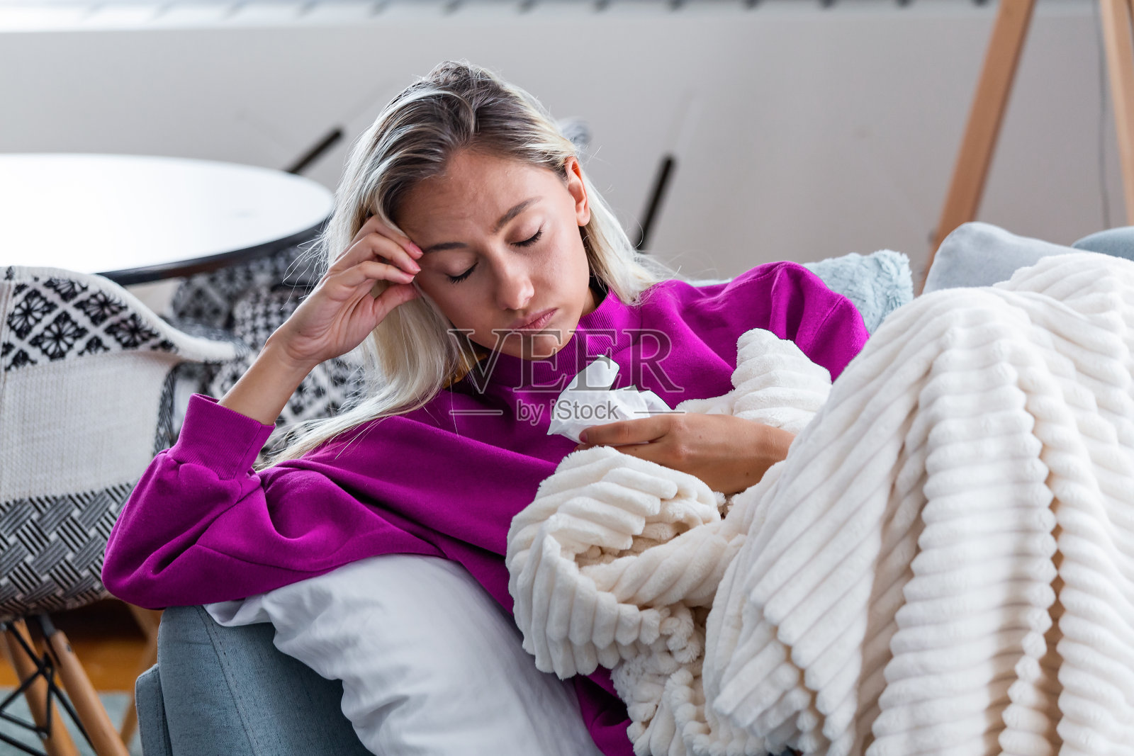 头痛的生病女人坐在毯子下。患有季节性感染、流感、过敏的生病女人躺在床上。盖着毯子的生病女人因高烧和流感躺在床上休息。照片摄影图片