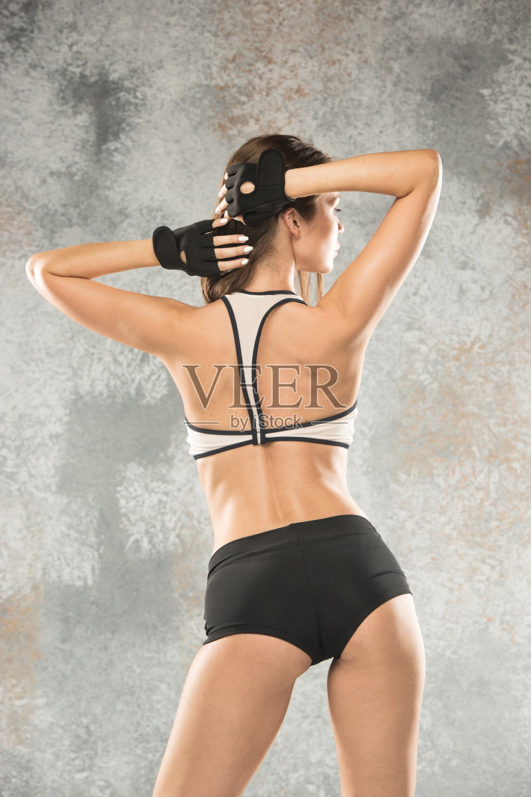 肌肉发达的年轻女运动员在灰色的石头背景照片摄影图片