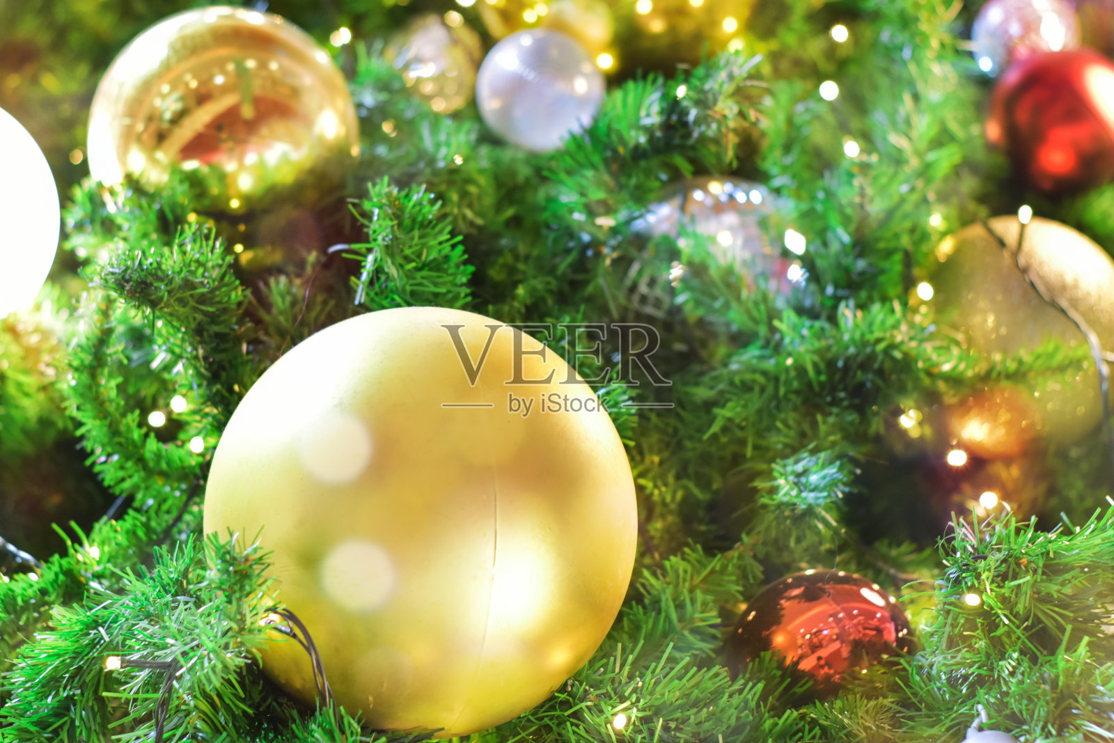 圣诞节的背景。圣诞树上的装饰物与散焦模糊的灯散焦。照片摄影图片