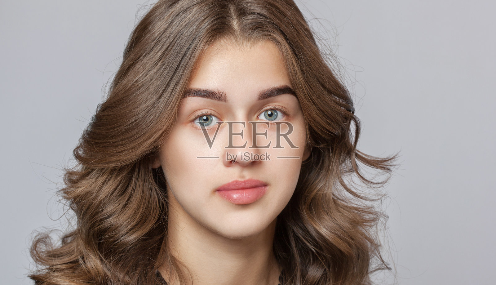 一个美丽快乐的女人的肖像卷发，干净的皮肤和浓密的眉毛美容院。睫毛扩展。脸特写。化妆的概念。照片摄影图片