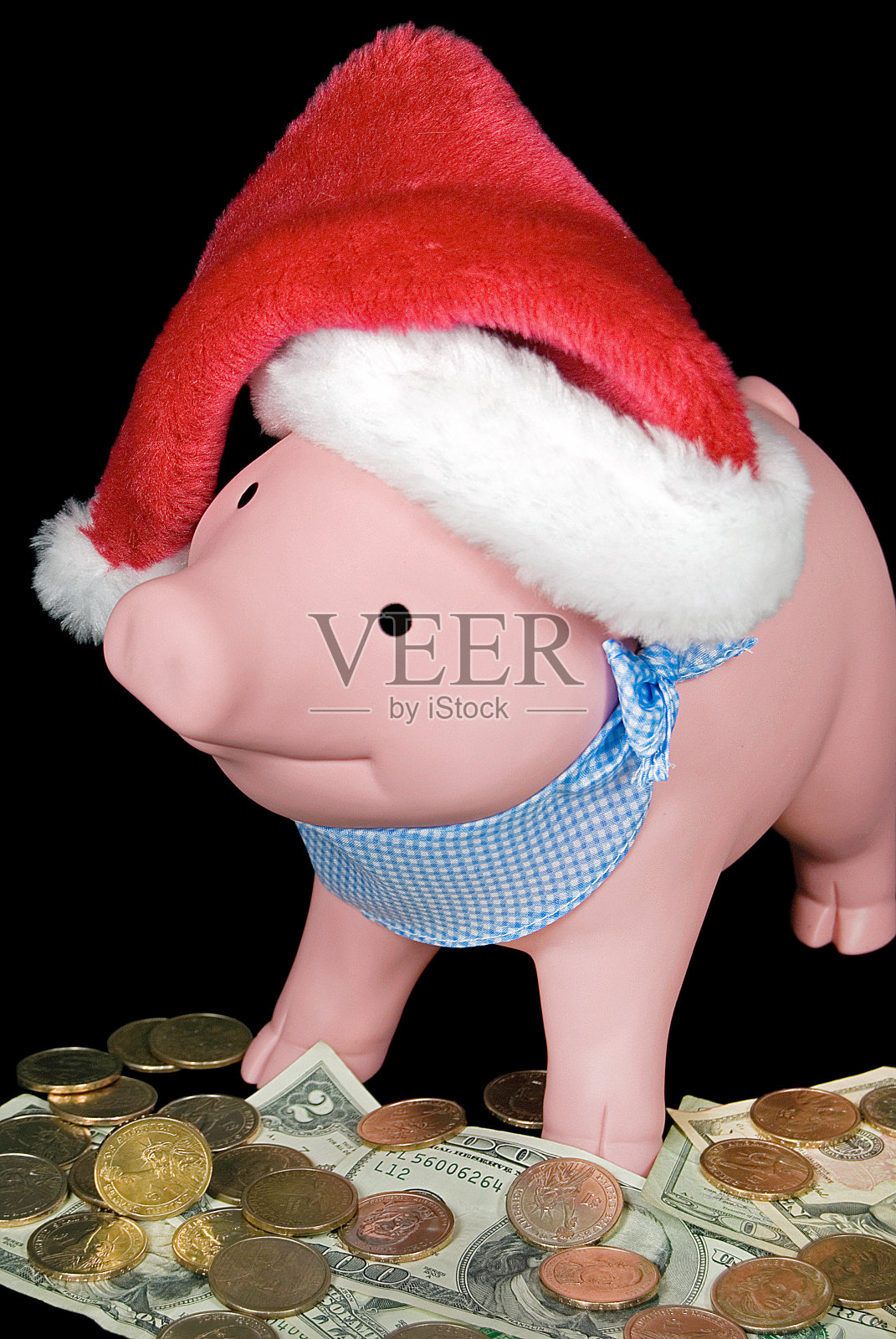 粉红色的储蓄罐上的钱和圣诞帽照片摄影图片