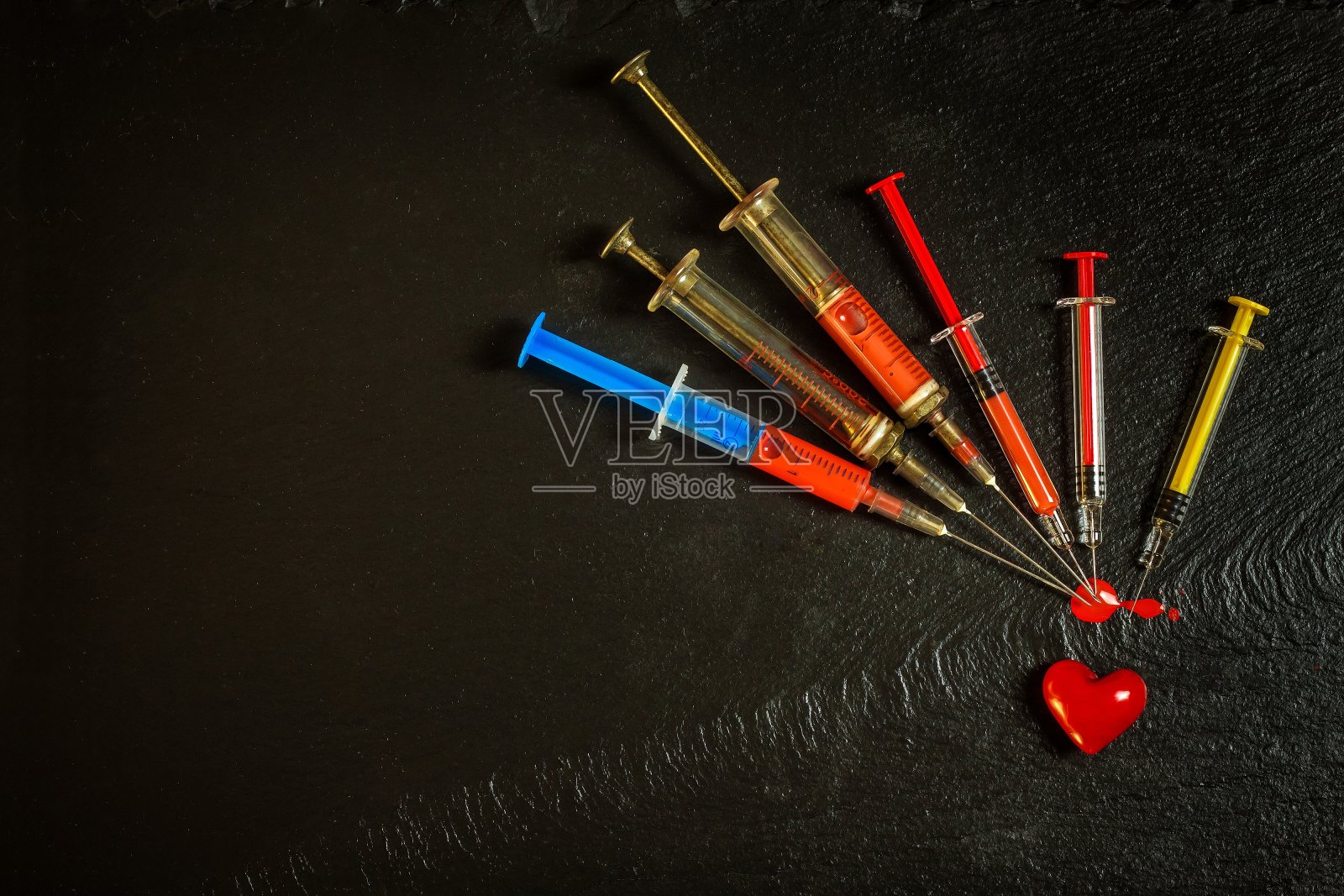 黑色背景上有注射器和血迹。感染艾滋病毒的风险。流感疫苗接种。血液测试。旧的注射器照片摄影图片