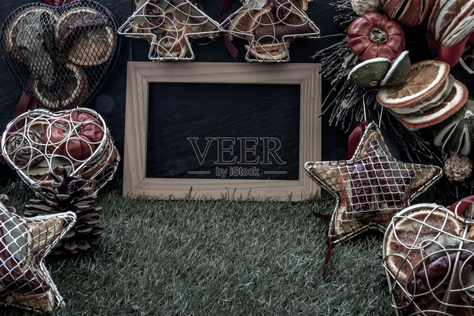 圣诞节装饰，棕色的天然松果和各种水果与空木架的设计元素，在草坪和黑暗的背景。照片摄影图片