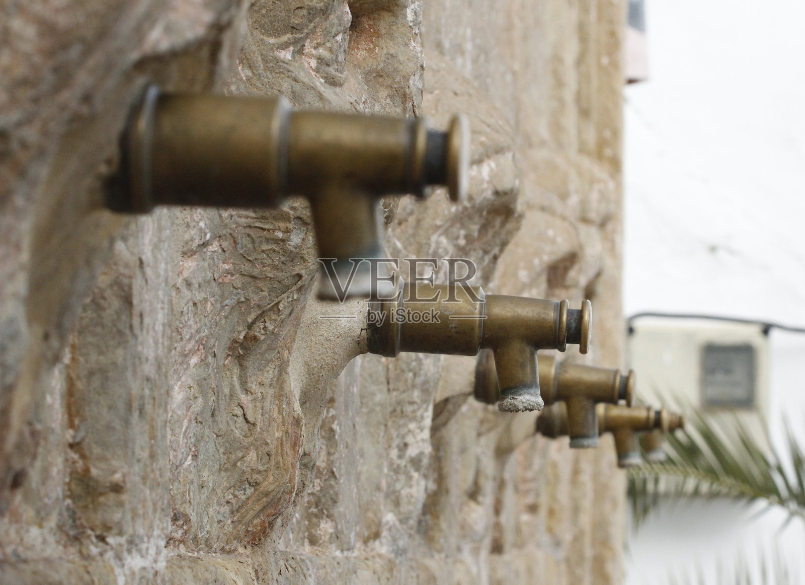石墙上有许多青铜饮水龙头照片摄影图片