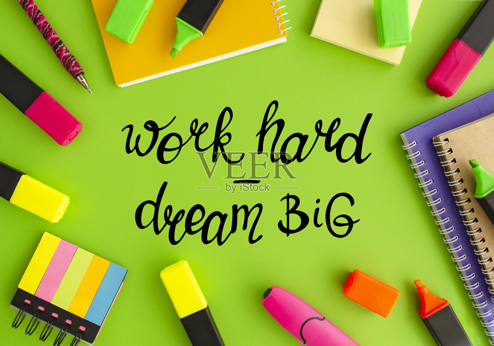 努力工作，梦想远大。不同的文具在绿色背景上用手写字母，俯视图。照片摄影图片