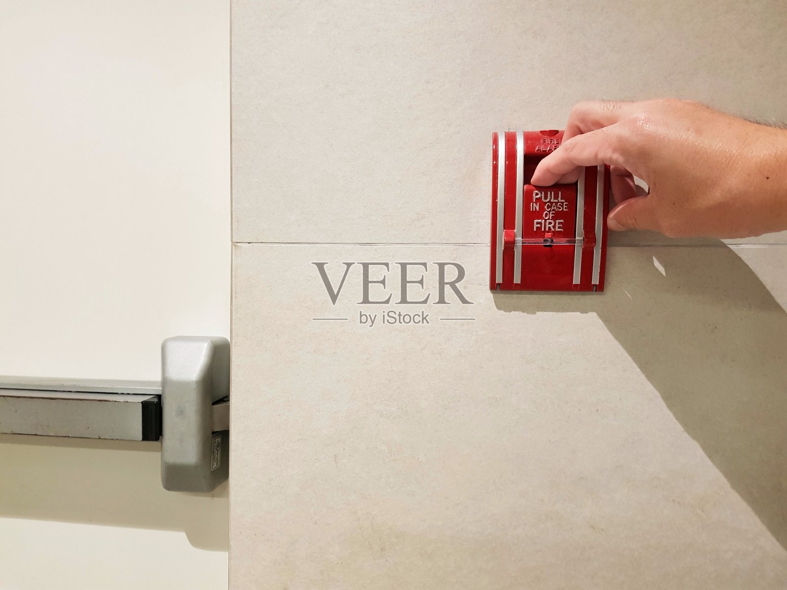 人们手拉红色火警按钮前的紧急消防出口通道。建筑或工业领域的安全保护计划。火灾探测器警报安全系统。照片摄影图片