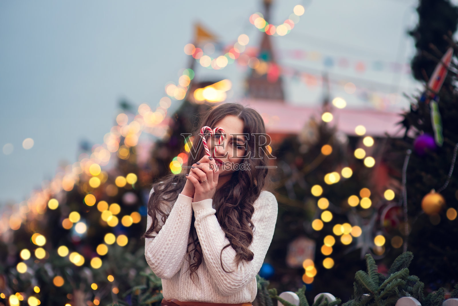 圣诞肖像快乐的女孩持有燃烧的烟花或室外，冬天装饰树的背景。新年假期在城市。照片摄影图片