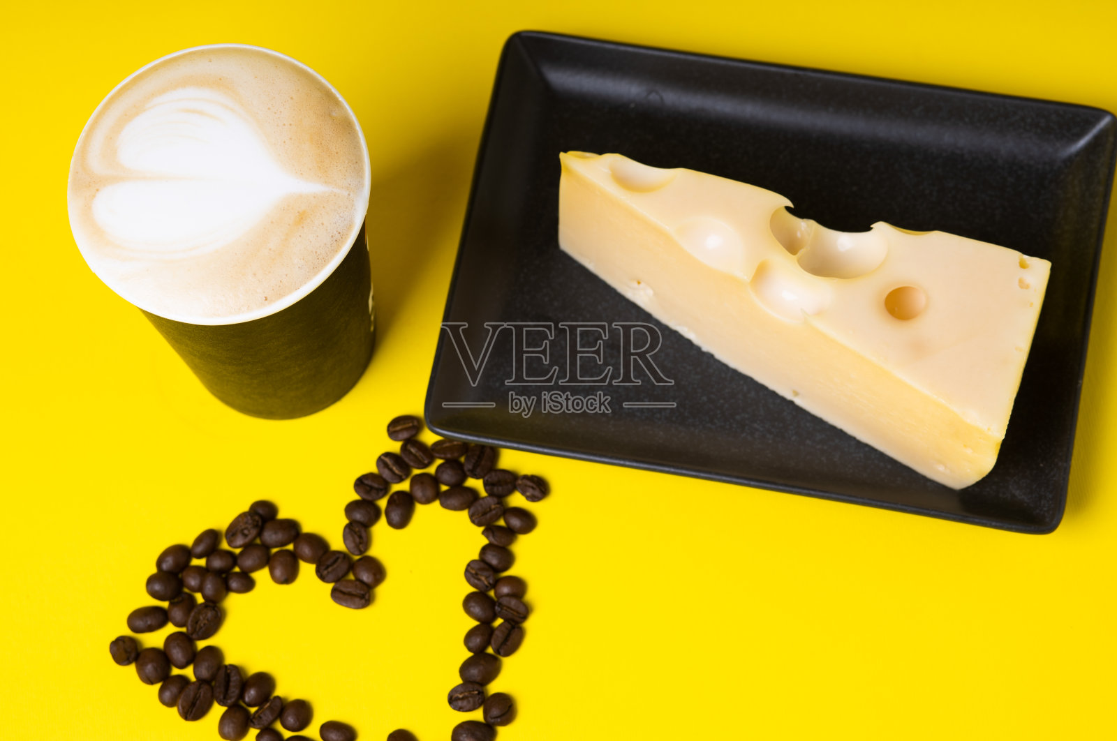 白色杯子，黄色背景的咖啡和心形的咖啡豆。照片摄影图片