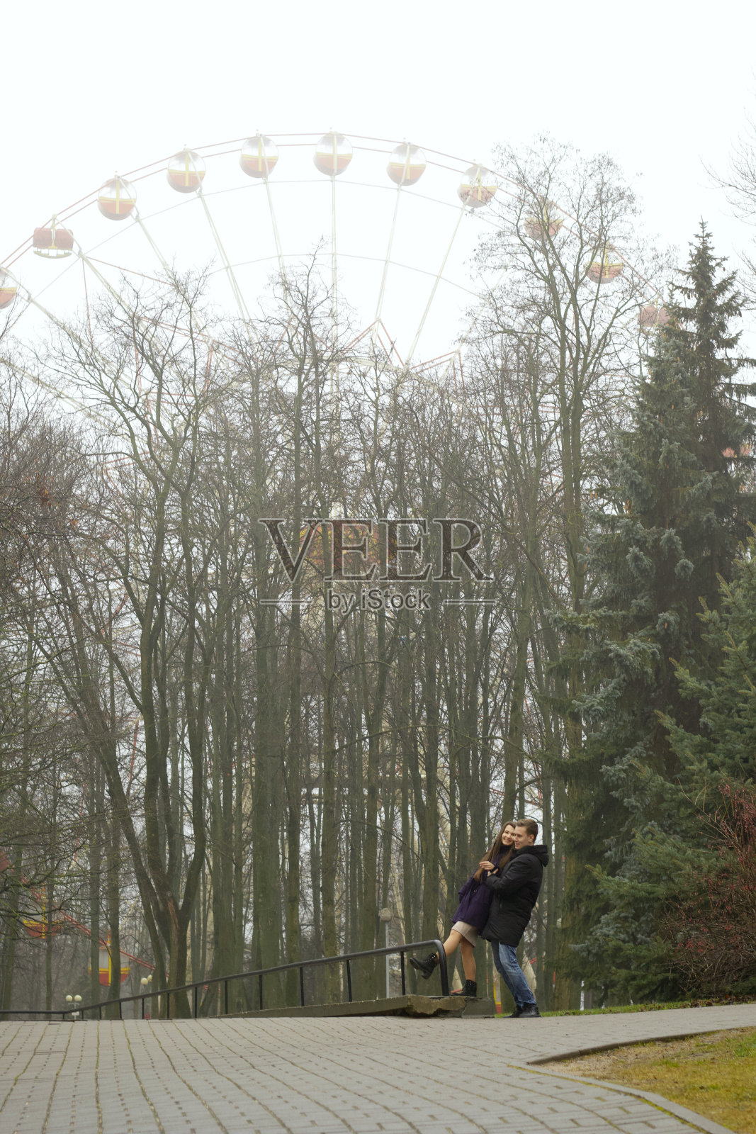 一对夫妇在深秋的公园里拍照。以摩天轮为背景。照片摄影图片