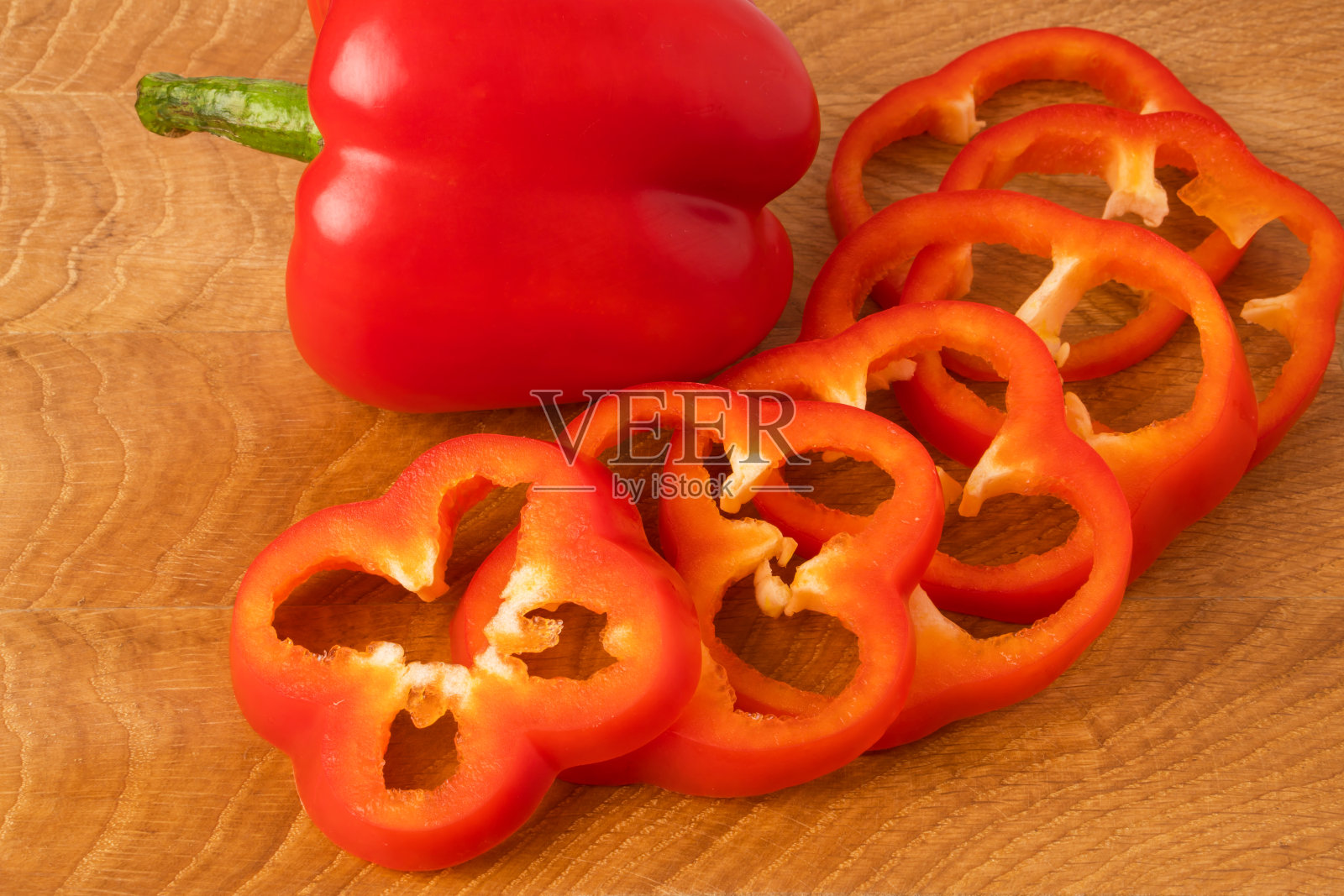 整个红甜椒和几片放在木板上照片摄影图片