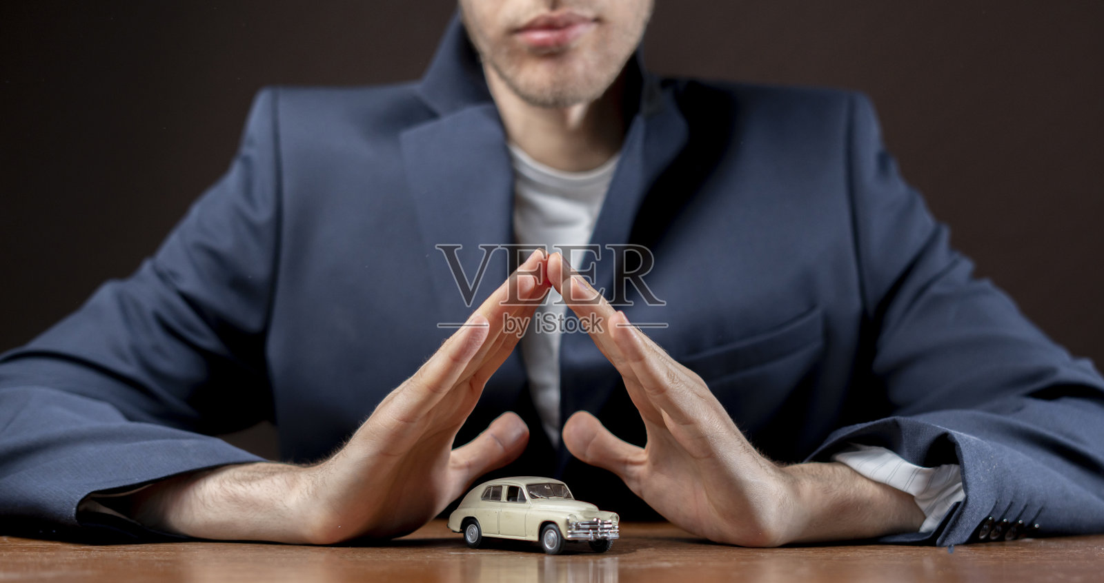 男人双手盖在桌子上的小车模型，保险概念照片摄影图片