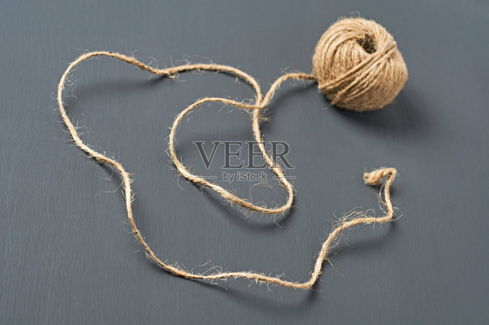 一个棕色的绳子球躺在车间黑色的混凝土桌上。特写镜头照片摄影图片