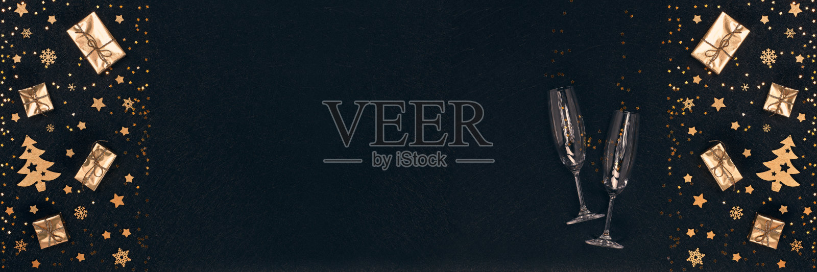 圣诞节和新年的背景。金色的装饰品，礼品盒，空的香槟酒杯。特别宽的全景横幅背景照片摄影图片