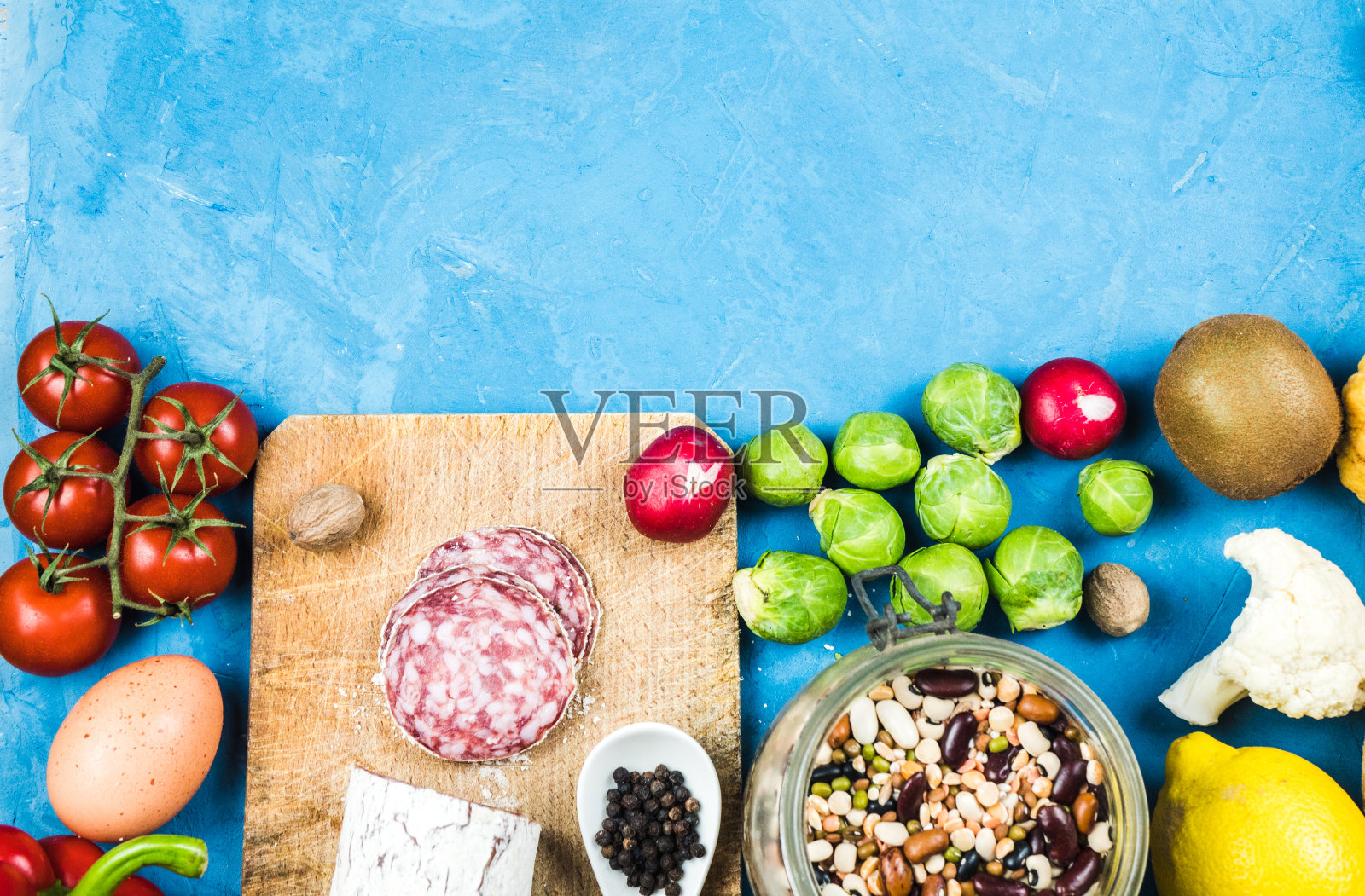 烹饪-新鲜的彩色有机蔬菜捕获从上面(俯视图，扁平的躺椅)。蓝色背景。版面与自由文本(复制)空间。素食食物。健康的食物照片摄影图片