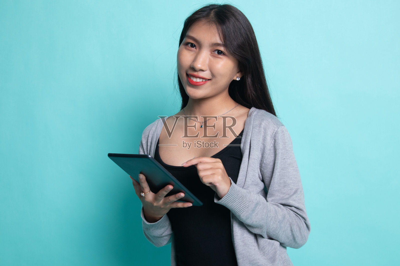 一个年轻的亚洲女人拿着一台平板电脑。照片摄影图片