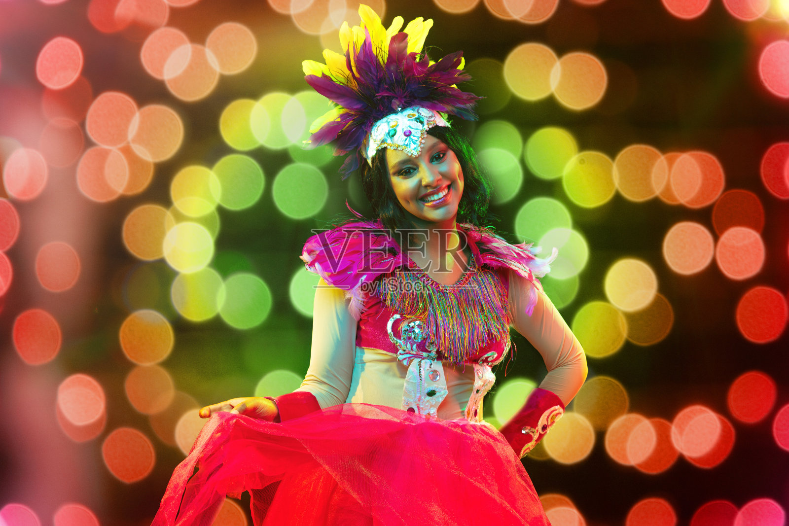 美丽的年轻女子在狂欢节面具和化妆舞会服装在五颜六色的灯光照片摄影图片