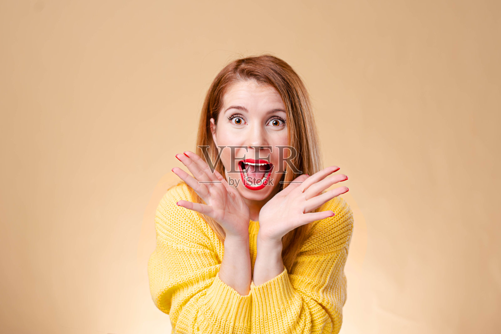 一个惊讶的女人戴着眼镜，穿着黄色毛衣在黄色的背景。看相机。照片摄影图片