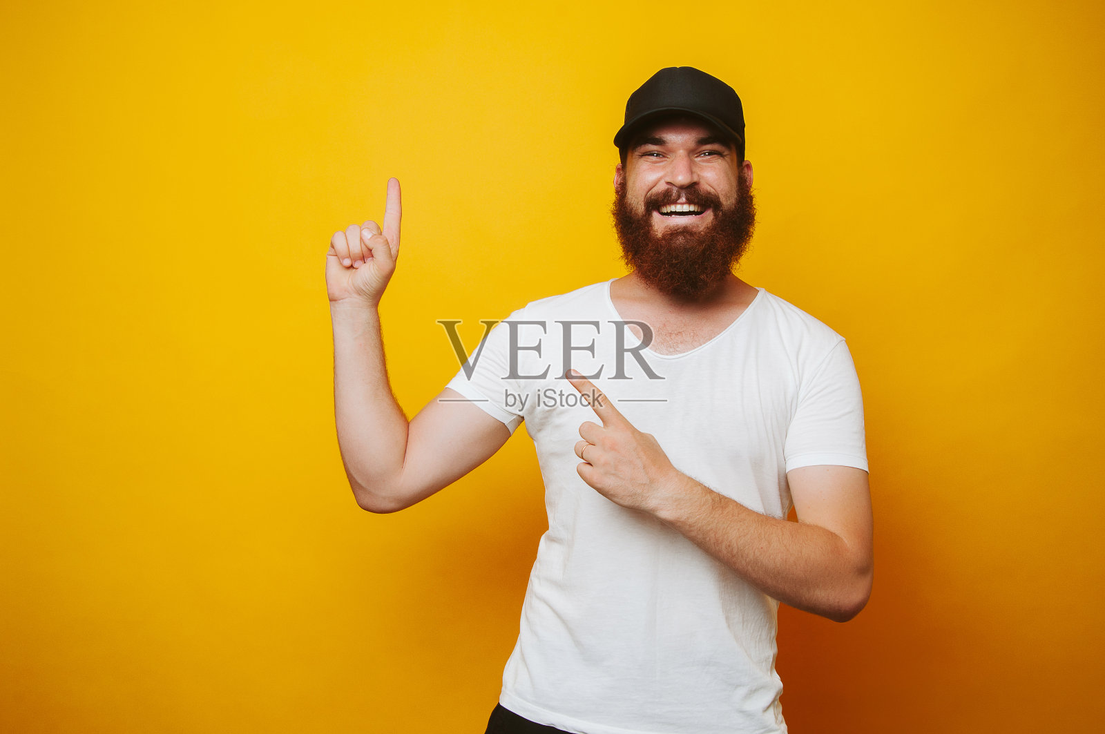 穿着白t恤的快乐大胡子男人指着文案照片摄影图片