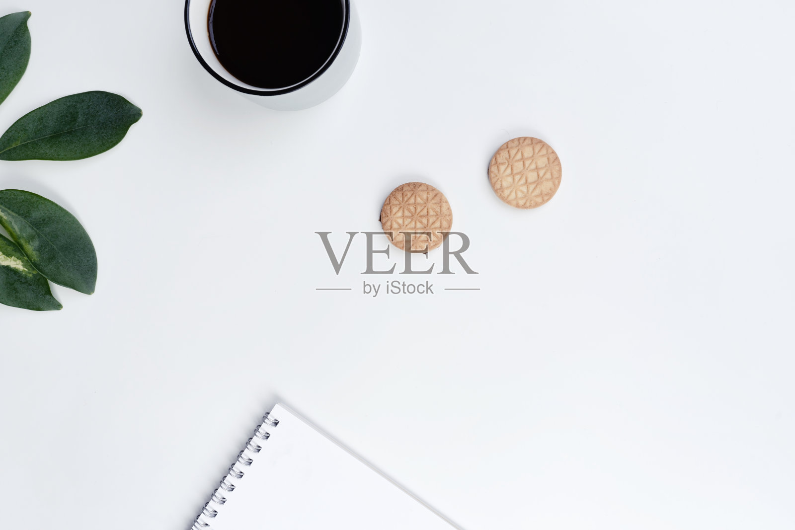 办公室的工作空间，一杯咖啡，饼干，绿叶，笔记本和钢笔在白色的背景。平躺，俯视图照片摄影图片