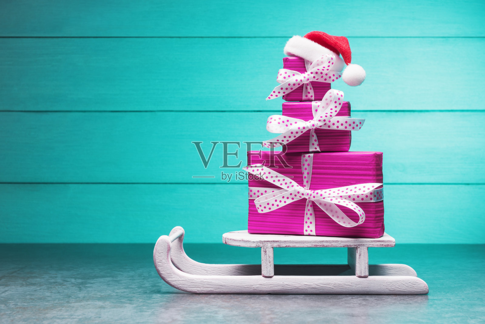 圣诞老人雪橇上的粉色礼盒，绿松石背景照片摄影图片
