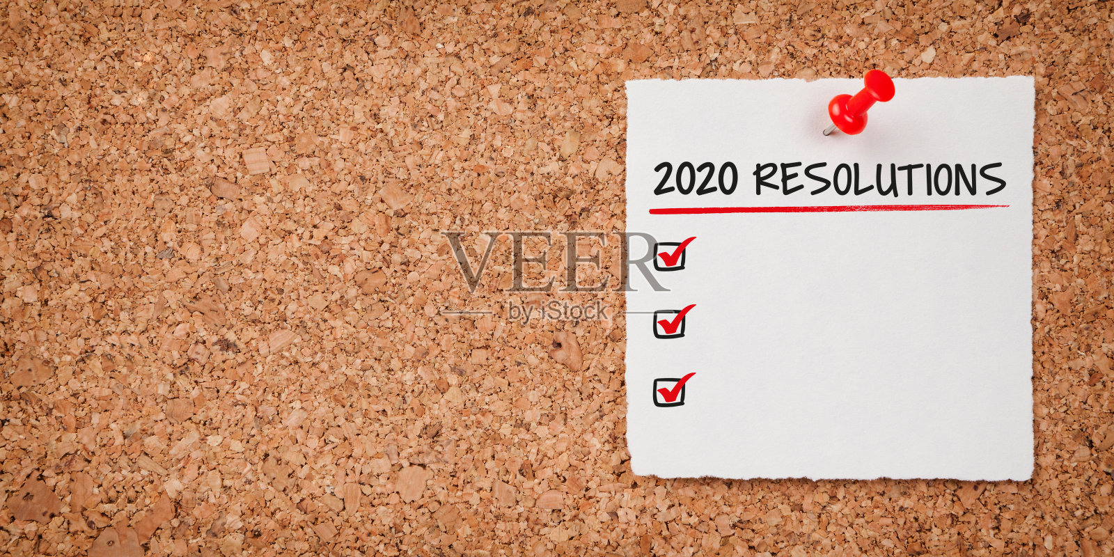 写着2020年新年决心的白色便签和软木板上的红色大头钉照片摄影图片