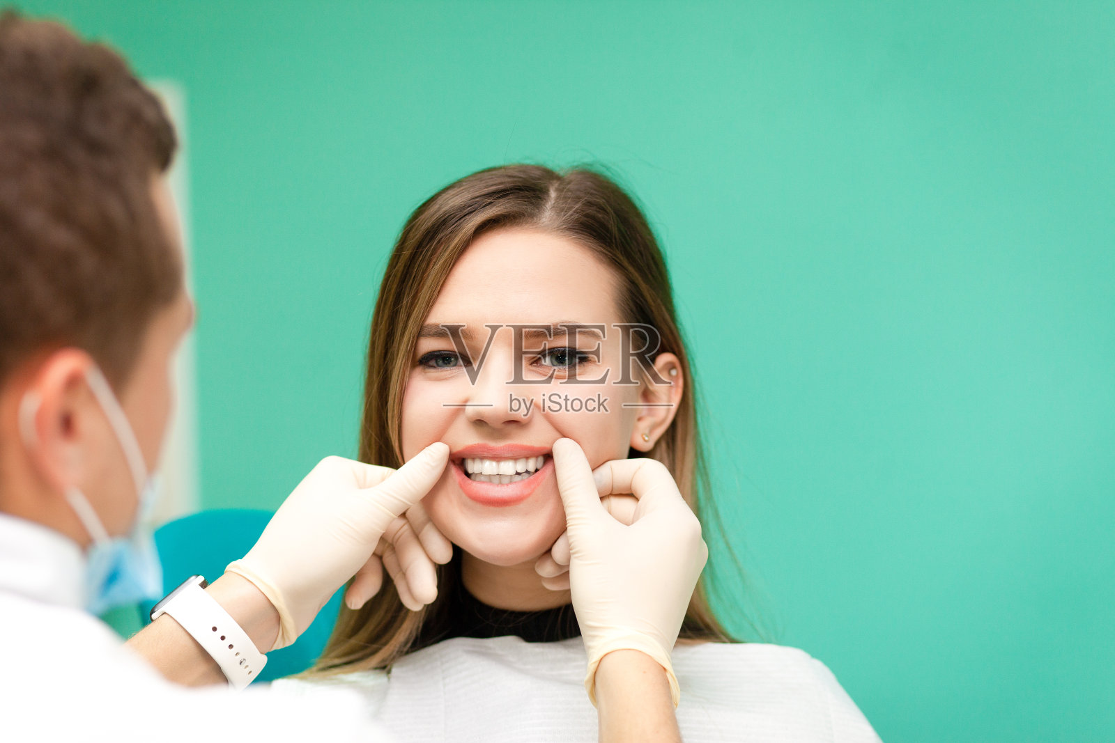 年轻女孩在看牙医。牙医正在检查一个女孩的牙齿照片摄影图片