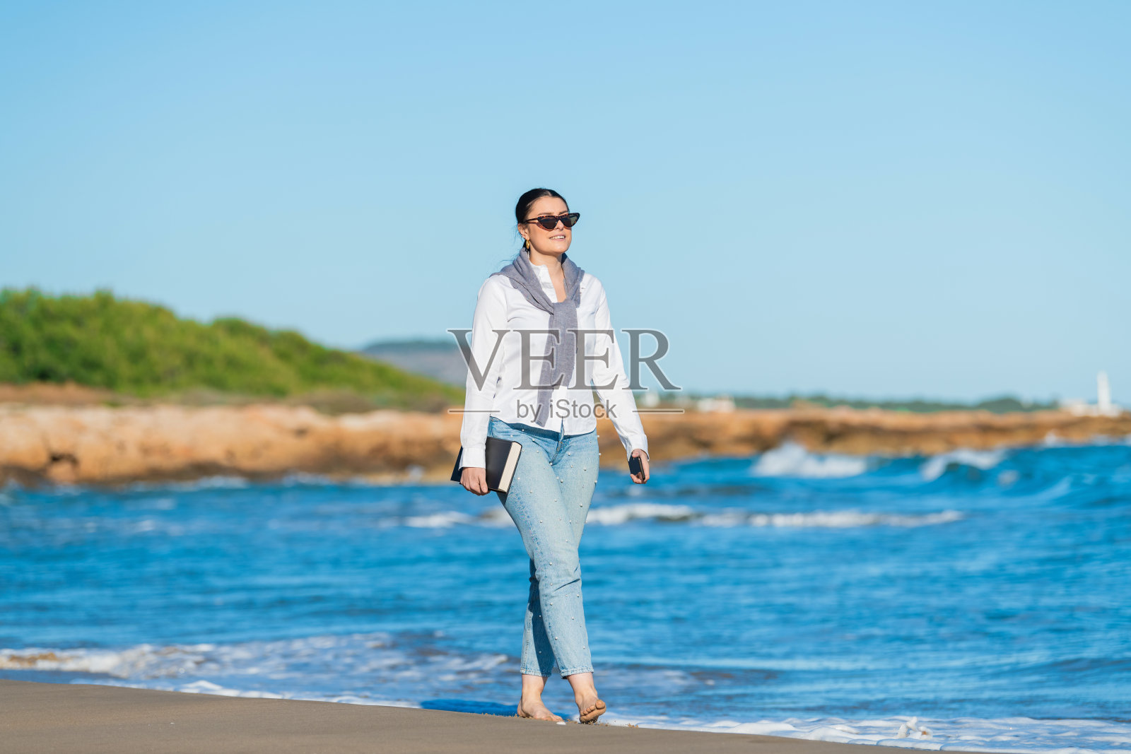 微笑的女人在阳光明媚的海滩上散步照片摄影图片