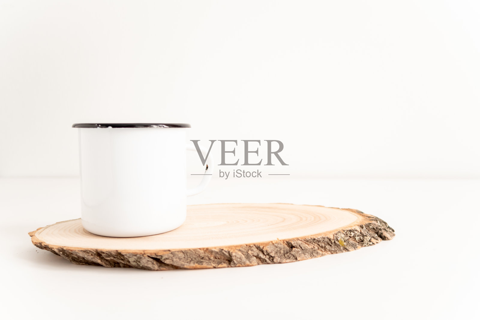 搪瓷马克杯模拟与木质切割树节在白色桌子上。波希米亚设计的锡杯在白色背景与复制空间的图像或文字照片摄影图片