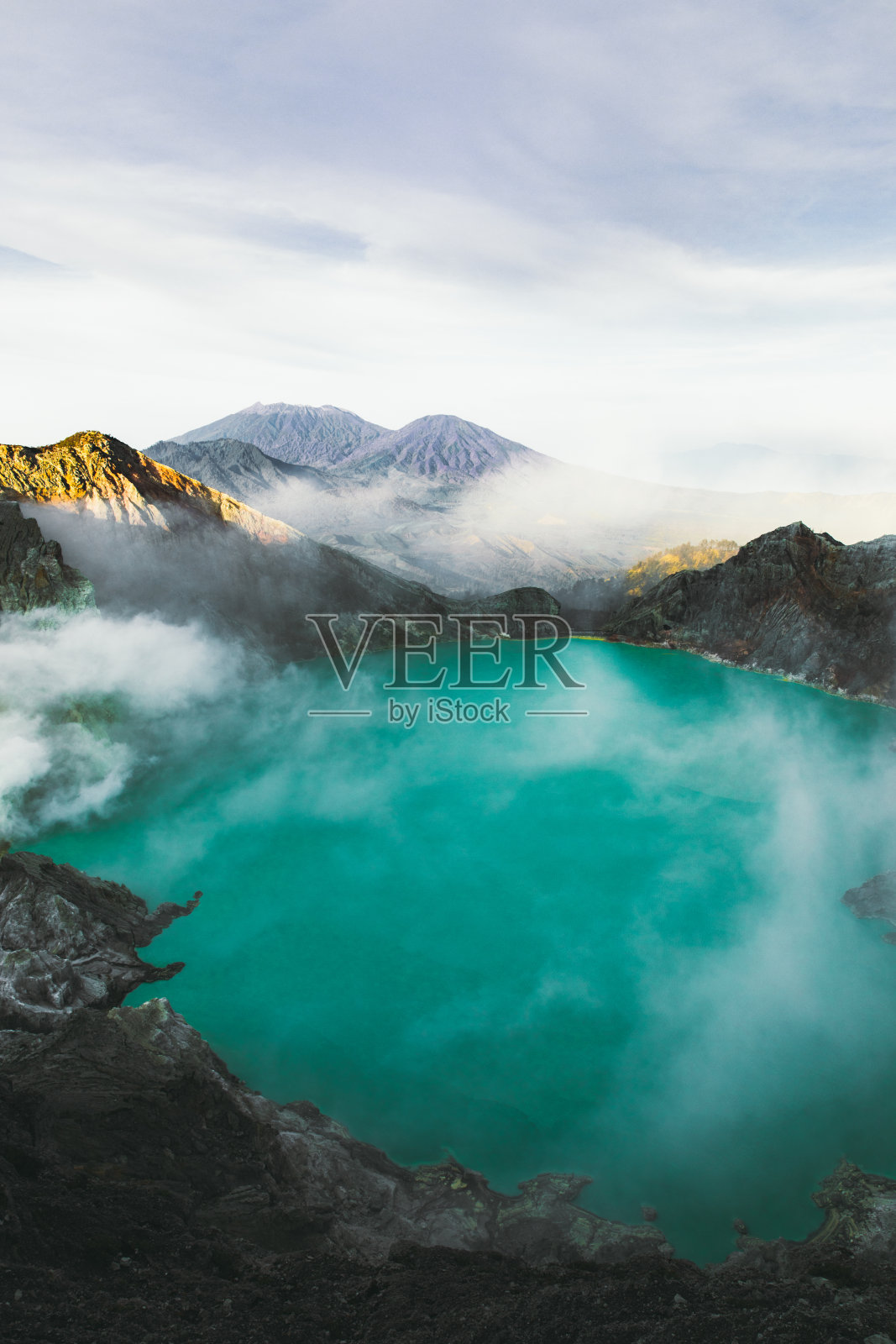 印度尼西亚东爪哇的伊真火山火山口的绿松石色湖泊，山脉和硫磺蒸汽的戏剧性景色照片摄影图片