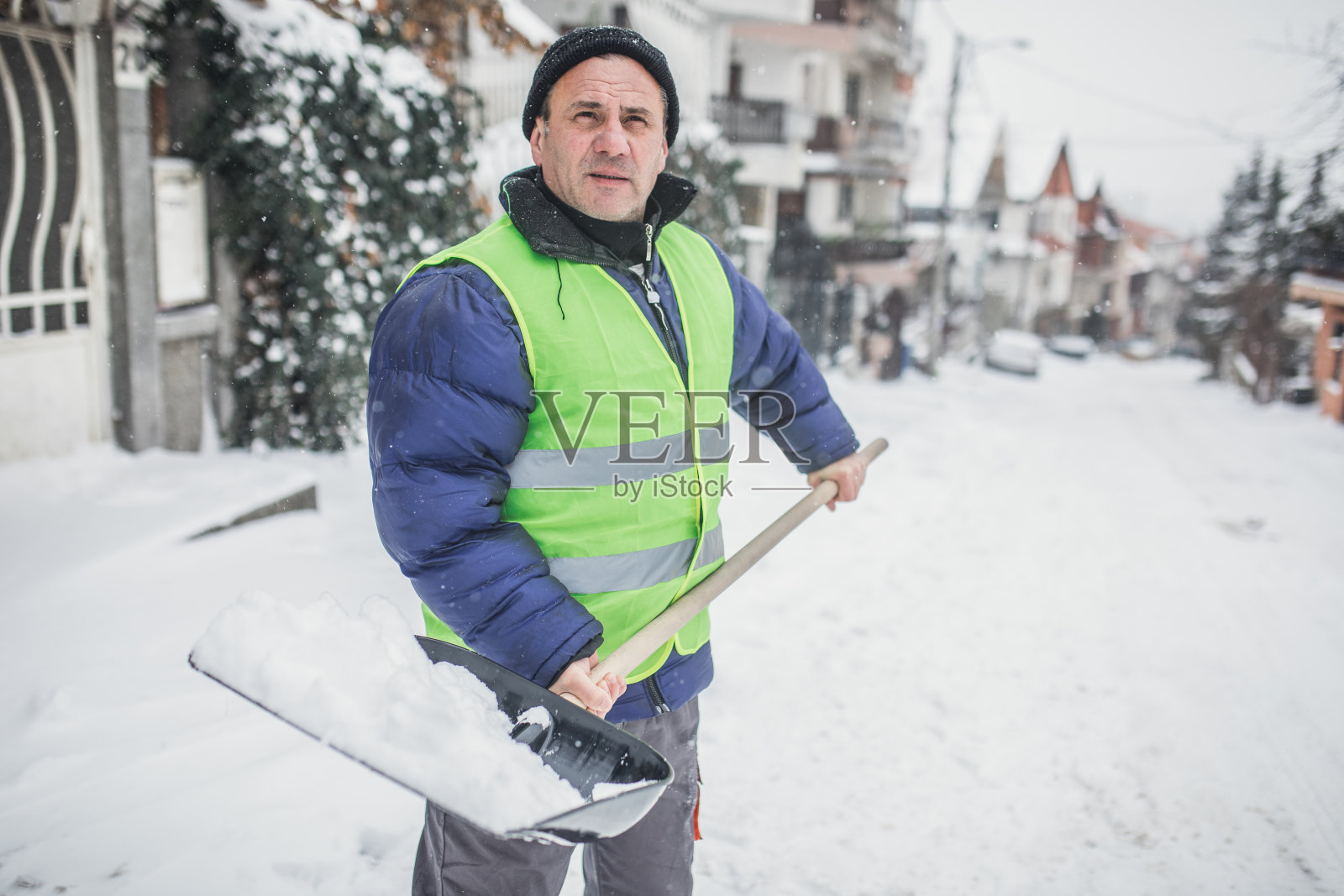 一个成熟的男人在清扫屋前的积雪照片摄影图片