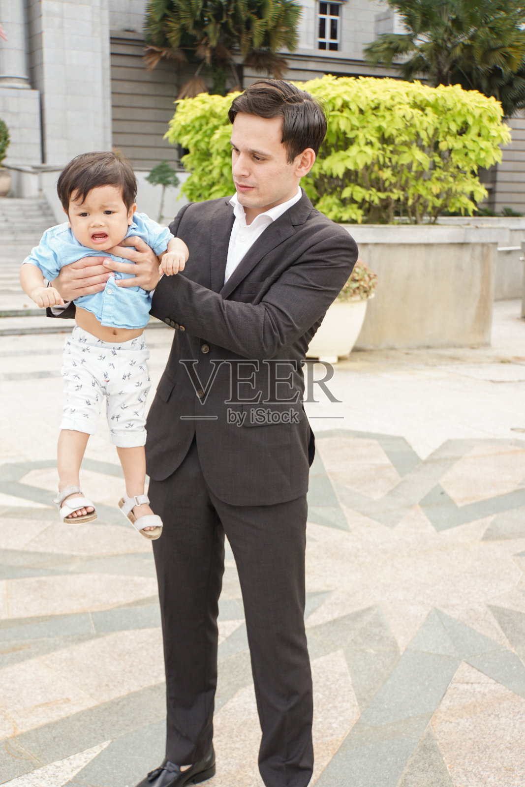 男人抱着哭泣的男婴照片摄影图片