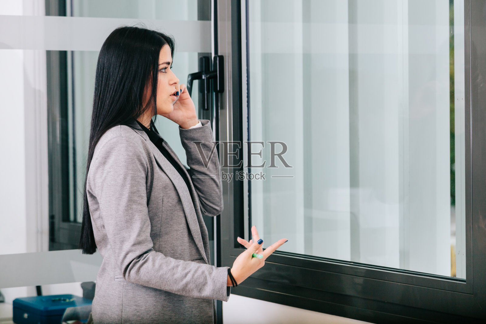 一位女商人在办公室靠窗边打电话照片摄影图片
