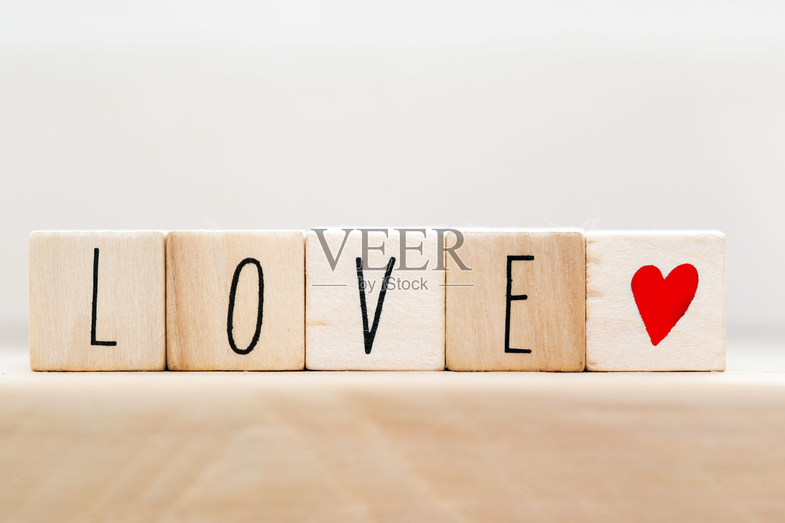 “爱字”贴在红心木制立方体上，近距离靠近白色背景照片摄影图片