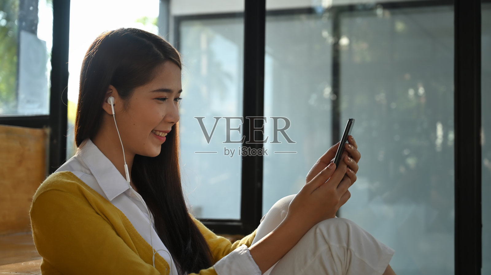 女人用手机听流媒体音乐。照片摄影图片